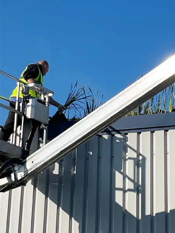 A drainage engineer clearing gutters using a boom lift on an industrial estate in Ealing, London.