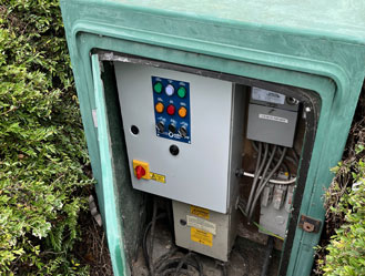 Jet and Drain technician servicing an outdoor sewage pump switchboard during routine maintenance.
